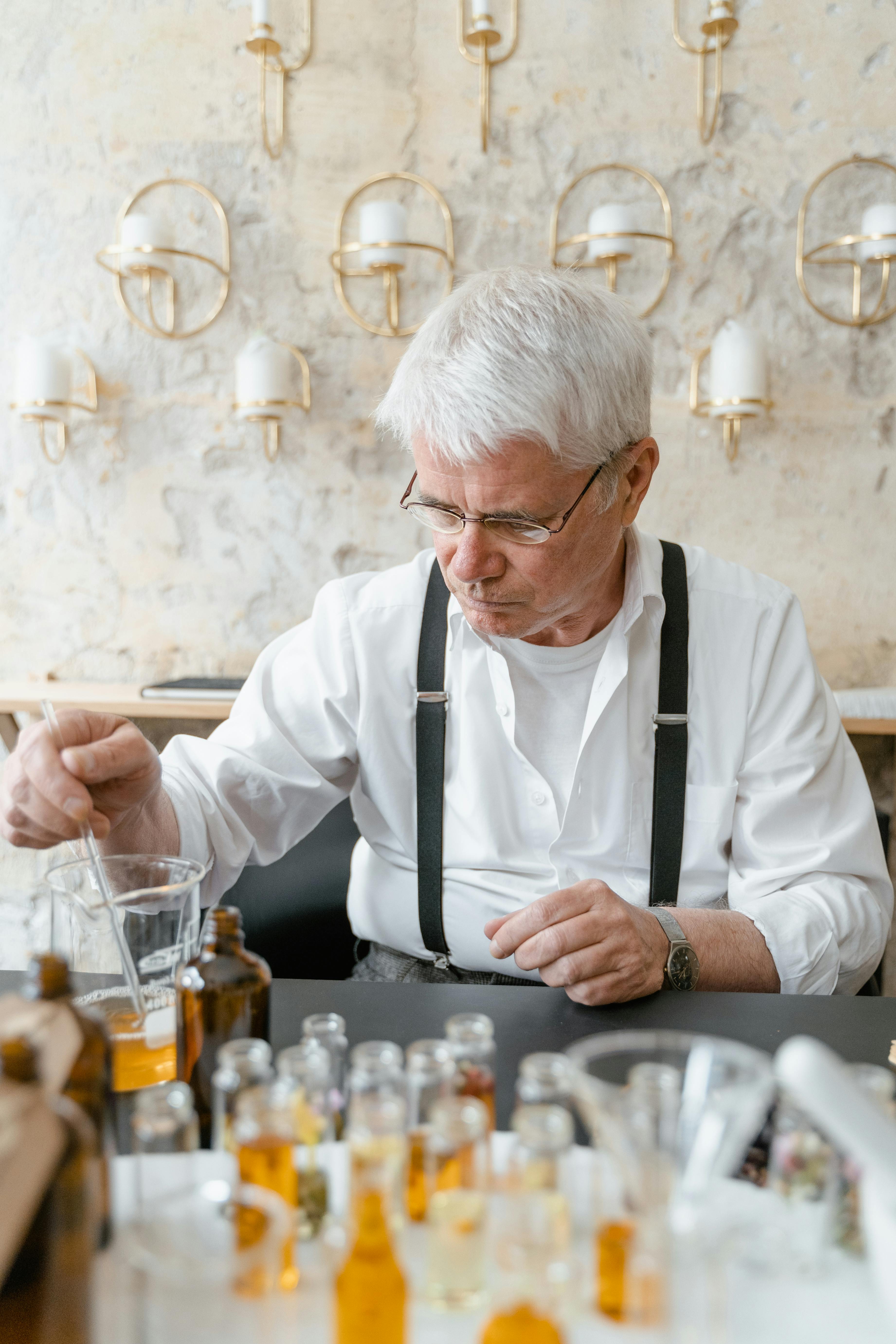 elderly man sitting at table with small bottles