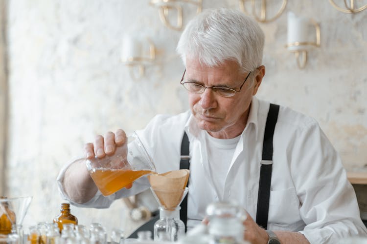 Gray Haired Man Pouring Liquid On Glass Bottle