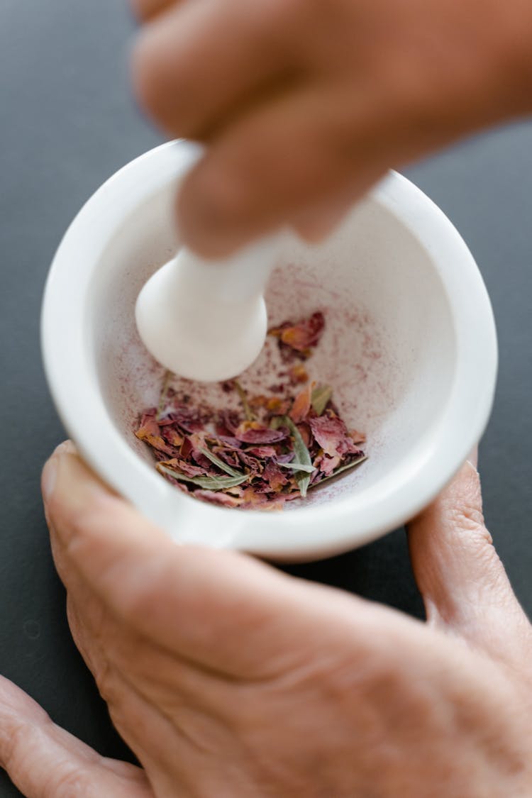 Hand Crushing The Petals Using Mortar And Pestle 