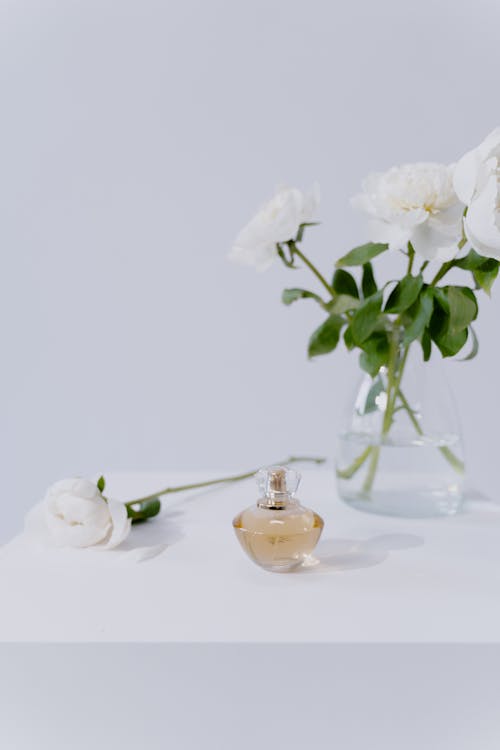 Free A White Flowers Near the Perfume Bottle on the Table Stock Photo