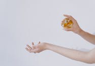 Close-up of elegant hands spraying perfume, showcasing beauty and luxury on a white background.