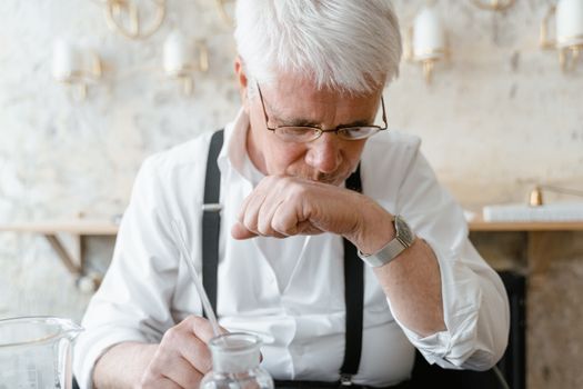 A senior man in white shirt and eyeglasses experiencing aromatherapy indoors.