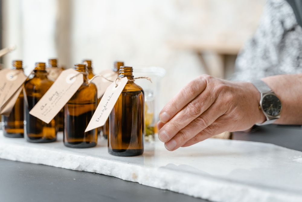 A row of amber material bottles with handwritten tags on the organ, a perfumer reaching for one