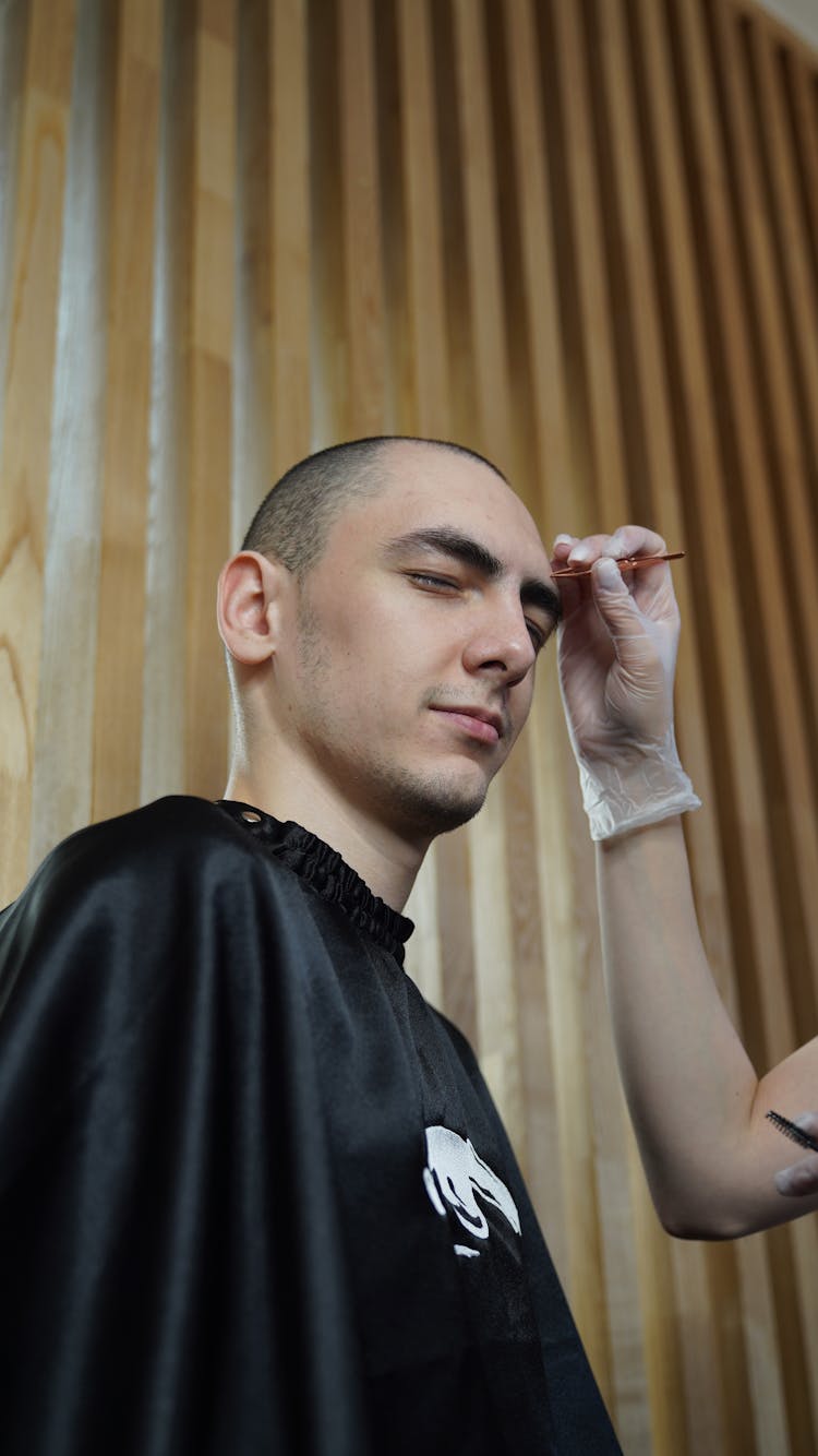 Person Plucking The Eyebrow Of A Young Man