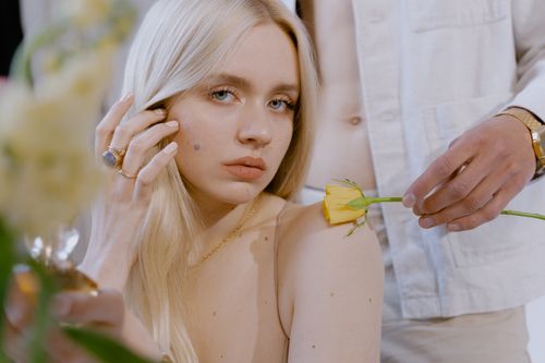 Free Beautiful portrait of a couple with a yellow flower, exuding romance and elegance. Stock Photo