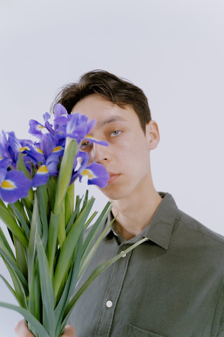 A Man Holding A Bunch Of Purple Iris Flowers