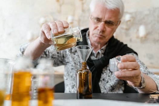 Elderly man carefully blending essential oils indoors for aromatherapy.