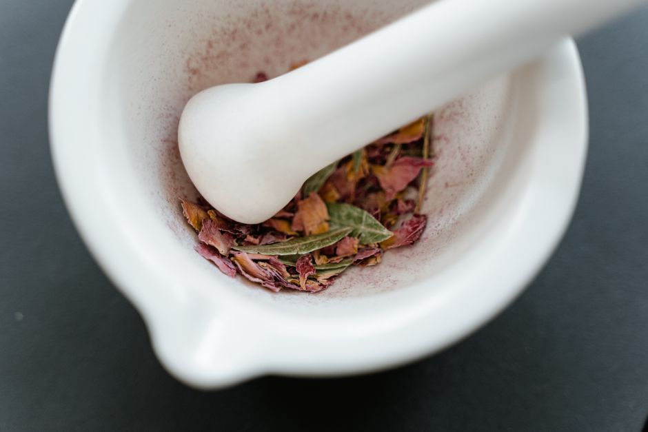 Dried herbal petals in a white mortar and pestle