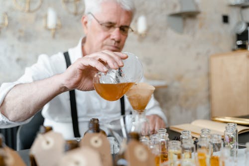 A Man pouring Brown Liquid in Glass Bottle