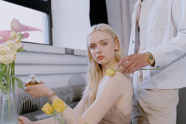 A Woman Sitting Holding A Perfume Beside Person Wearing White Denim Jacket