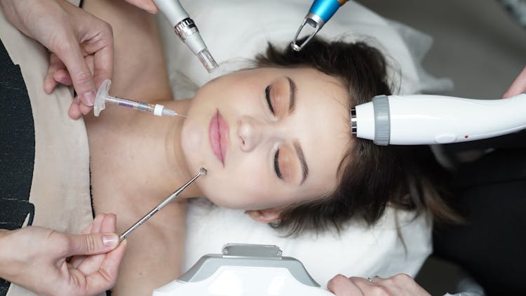 Hands Holding Cosmetic Equipment Hovering Above Womans Head