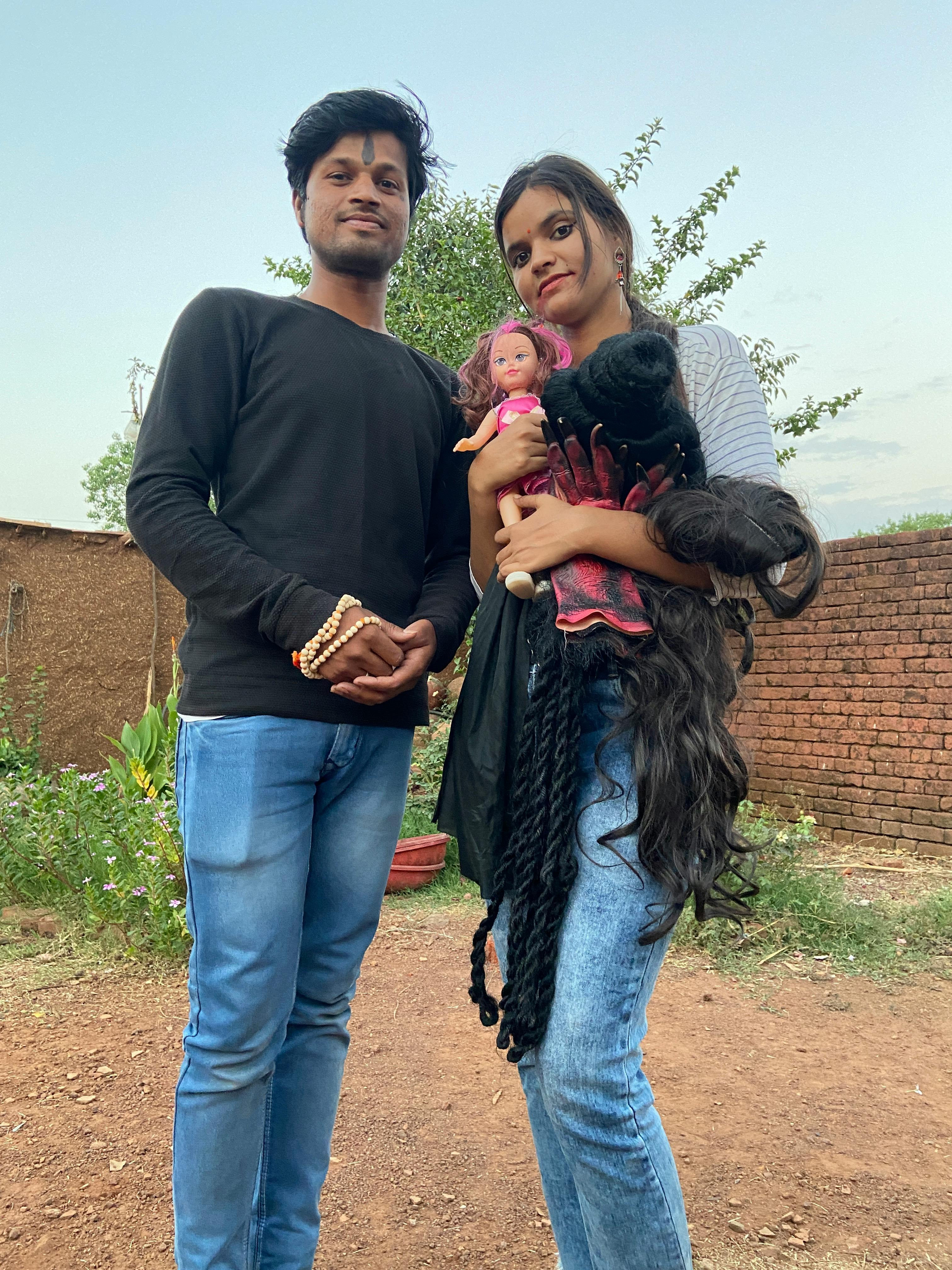 man in black long sleeves standing beside woman holding a doll