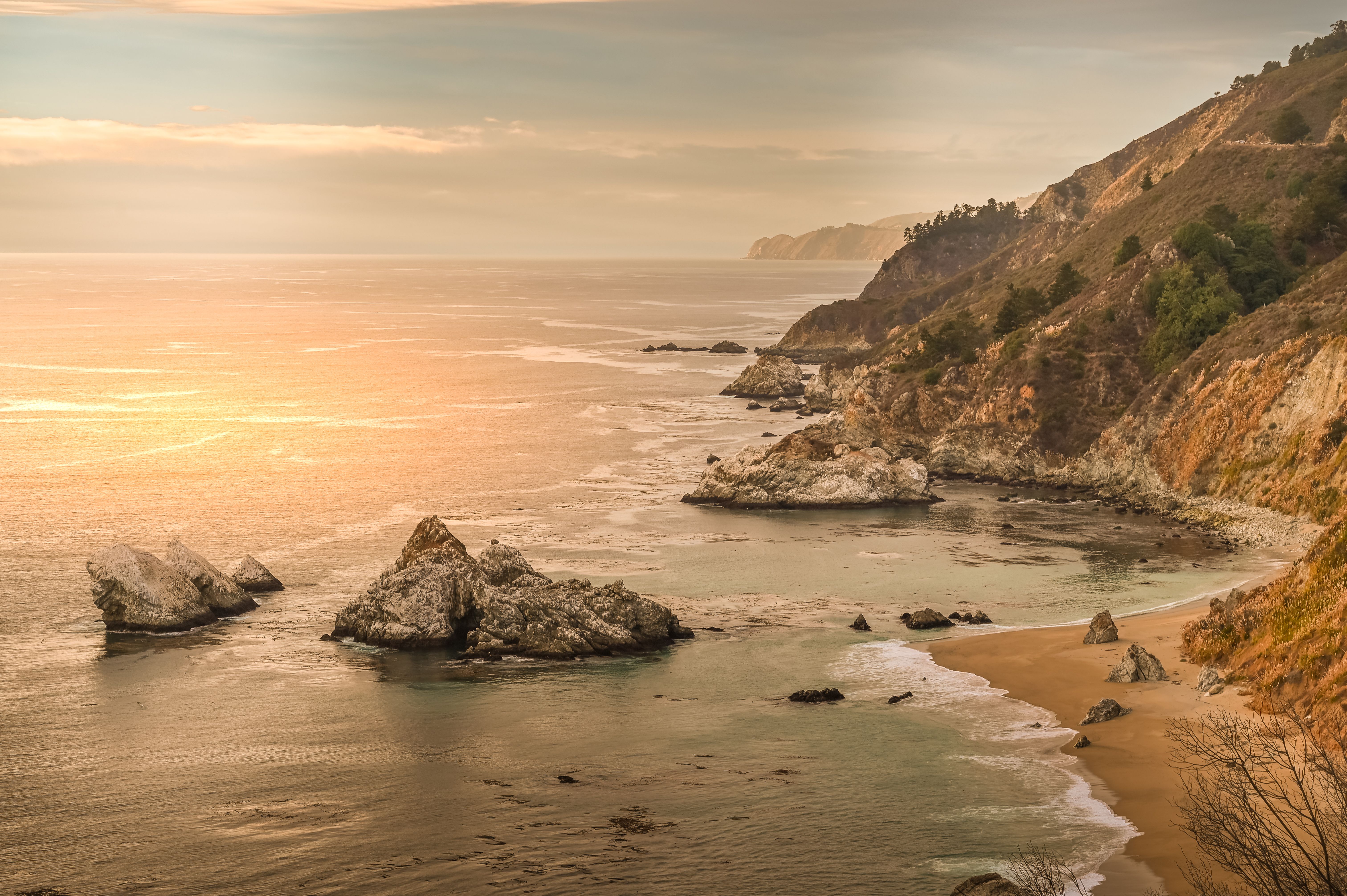 Beautiful sunset view of rugged cliffs and ocean waves along Big Sur coast, California.