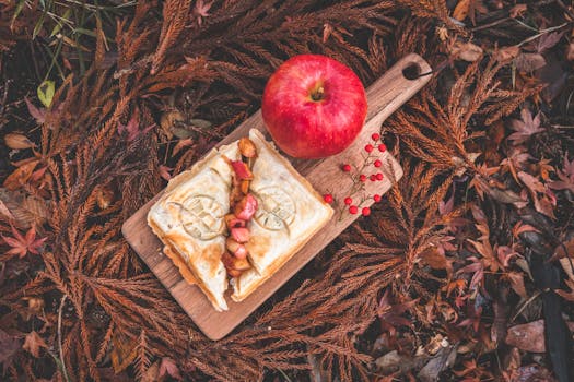 Delicious autumn-themed apple pastry on a wooden board surrounded by fall leaves.