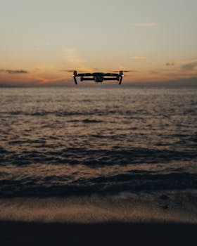 A drone hovers over a tranquil ocean during a stunning sunset, capturing the serene seascape.