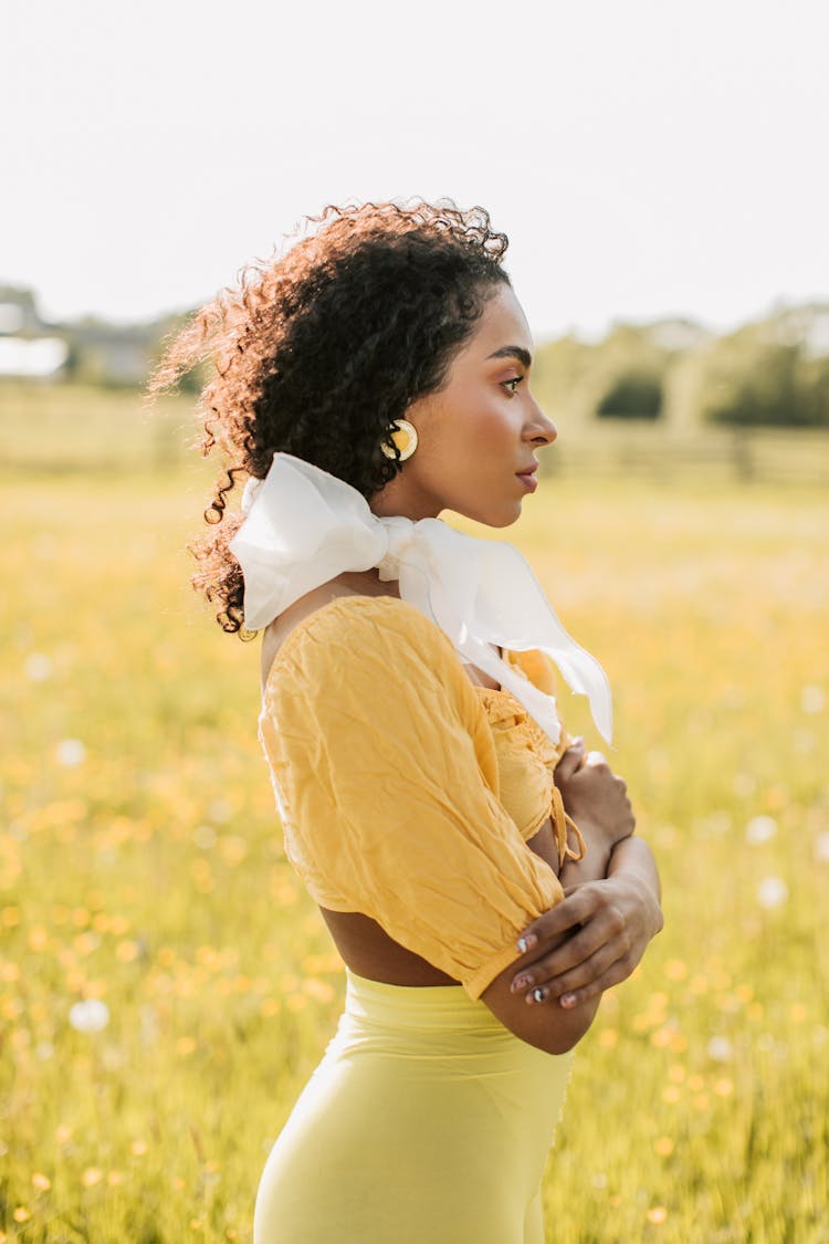 Woman In Yellow Crop Top Standing On The Grass Field