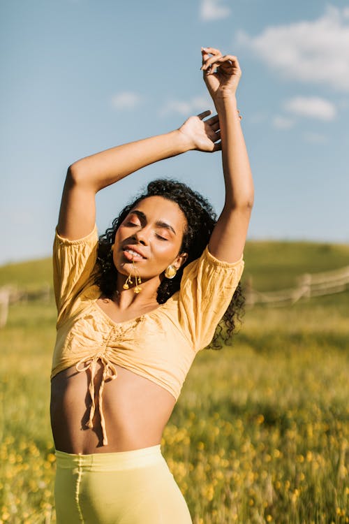 Free Woman in Yellow Crop Top Raising Her Arms Stock Photo