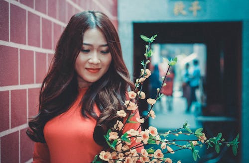 Free Woman Wearing Red Long-sleeved Shirt in Front of Flower Stock Photo