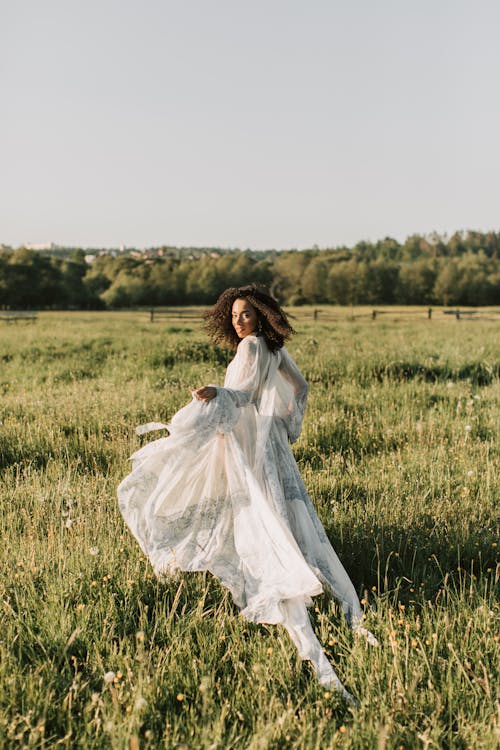 Woman in White Dress Walking on Grass Grass Field