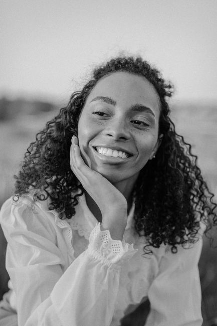 Black and white portrait of a woman with curly hair smiling warmly.