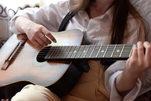 Woman in White Button Up Shirt Playing Brown Acoustic Guitar