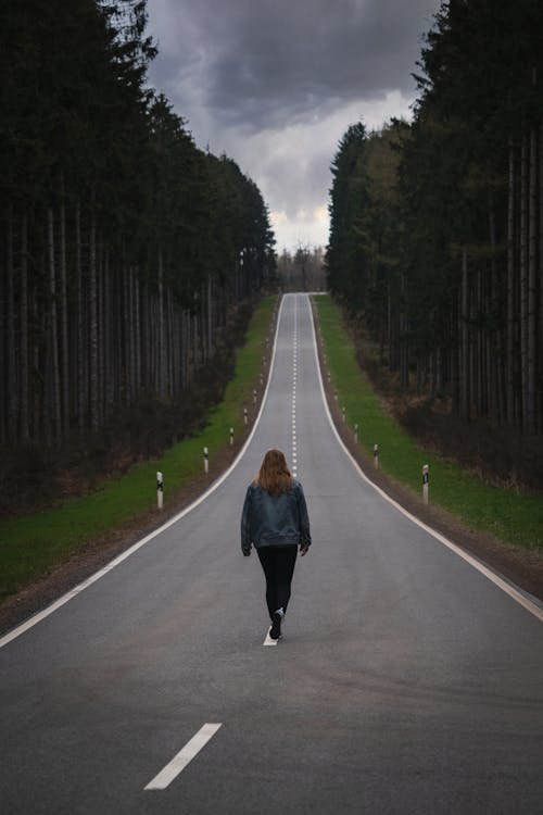 Free Woman Walking in the Middle of the Road Stock Photo