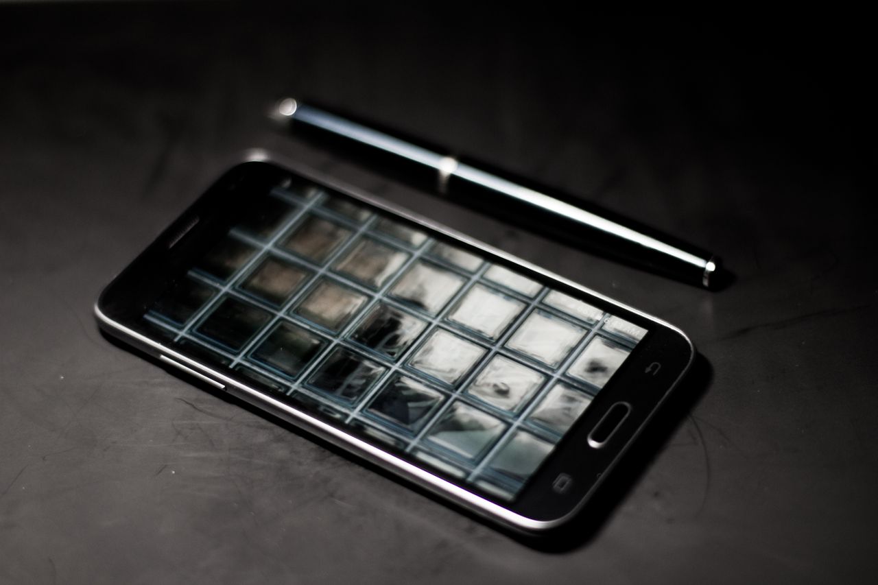 a sleek smartphone and pen on a modern desk reflecting geometric patte