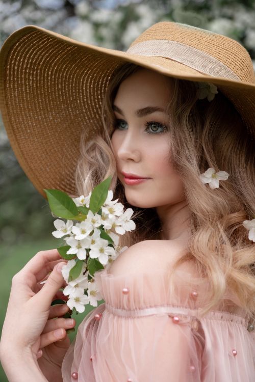 Free Stunning portrait of a woman in a straw hat with floral accents, showcasing beauty and spring fashion. Stock Photo