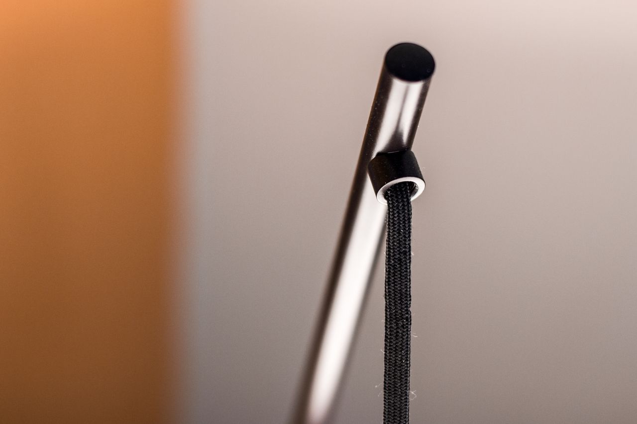 a close up of a shoelace tied to a sleek metal pole with a blurred bac