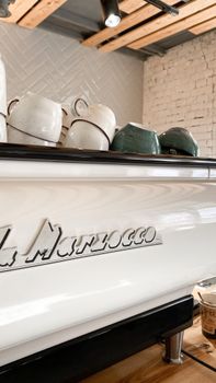 A stylish display of ceramic cups on a La Marzocco espresso machine in a modern cafe setting.