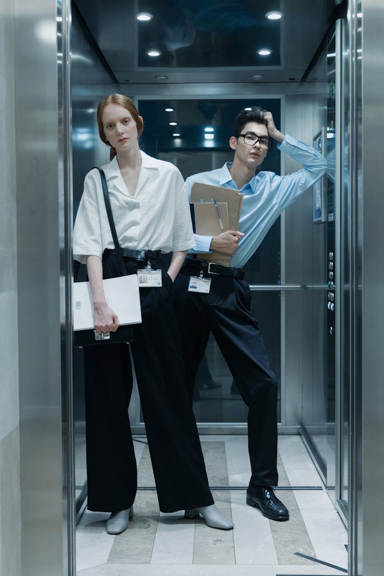 A Man And Woman Standing Inside The Lift