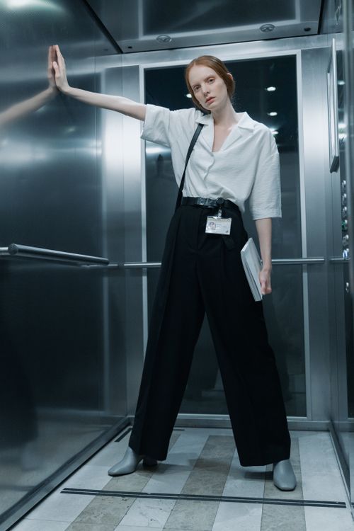 Free Female employee in casual wear stands confidently in an elevator holding a folder. Stock Photo