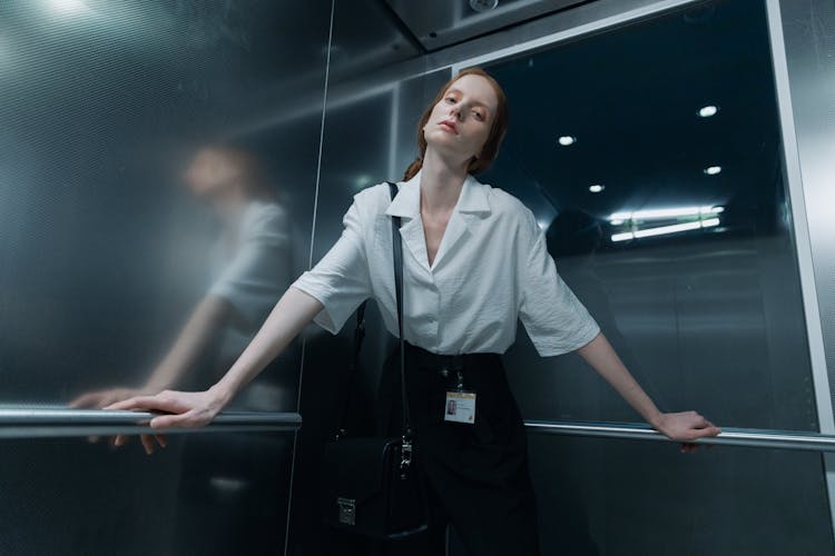 A Low Angle Shot Of A Woman In White Shirt Inside The Elevator