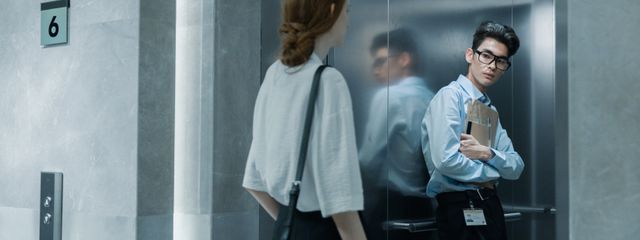 Office colleagues meeting in an elevator, showcasing a professional setting.