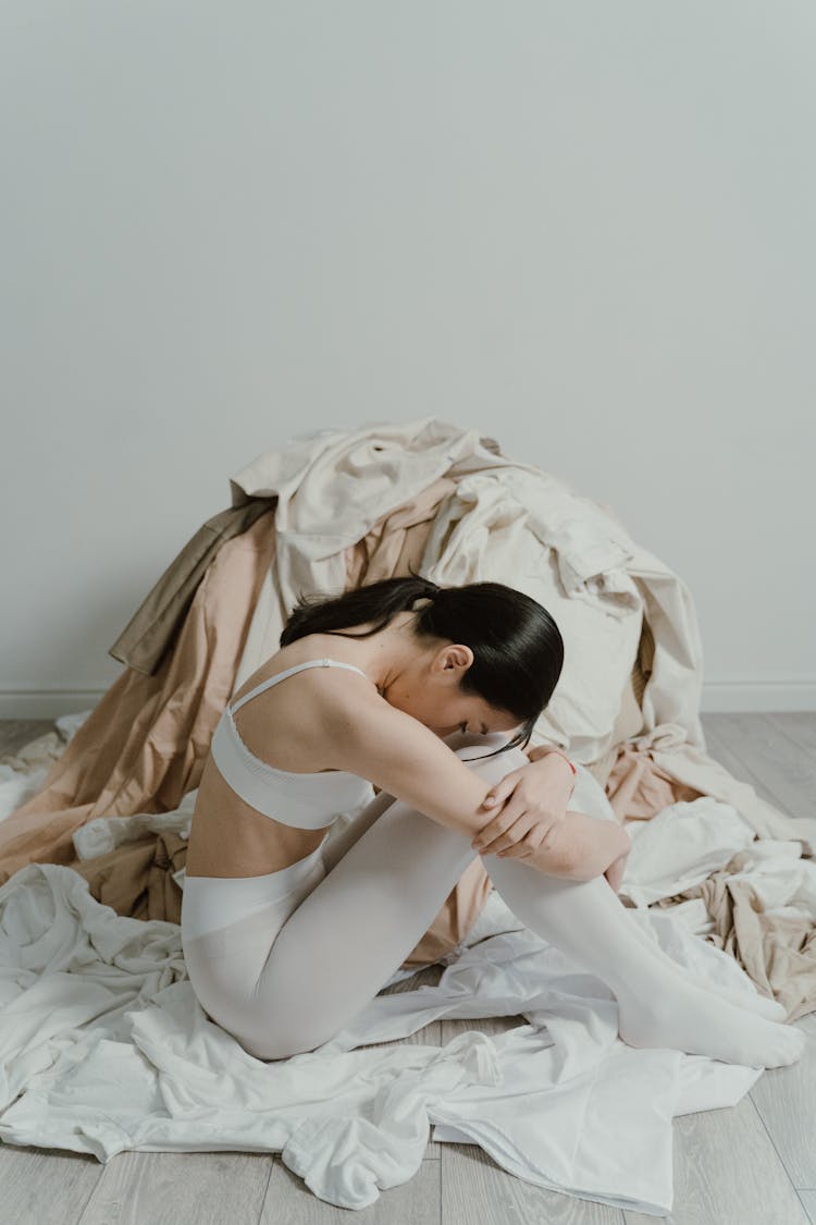 Woman Sitting Beside The Pile Of Clothes 