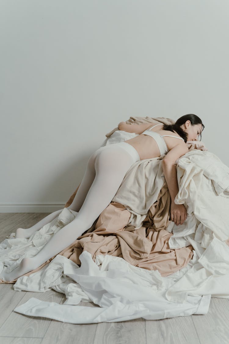 Woman Lying In A Heap Of Clothes 