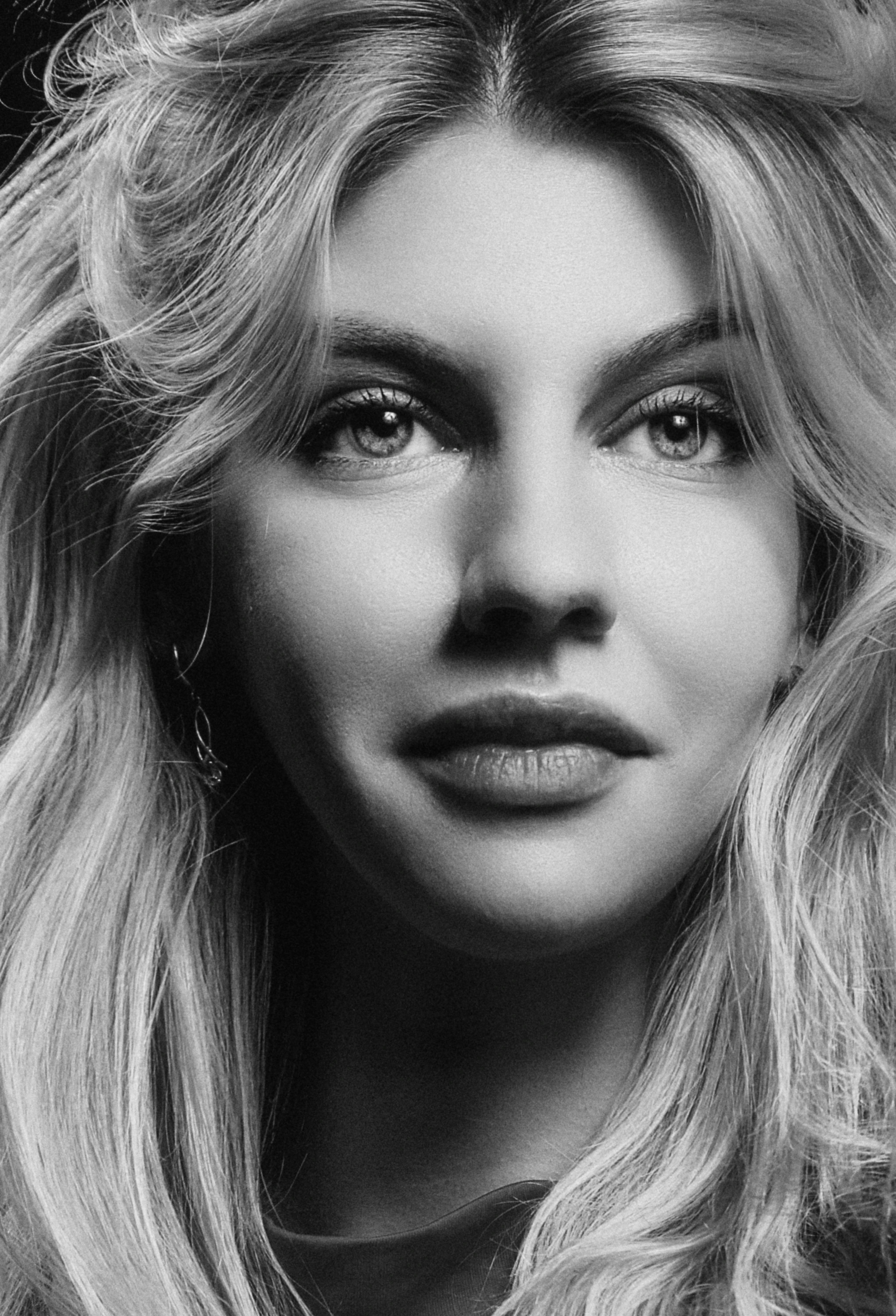 Close-up black and white portrait capturing a woman's serene expression and elegant hairstyle.