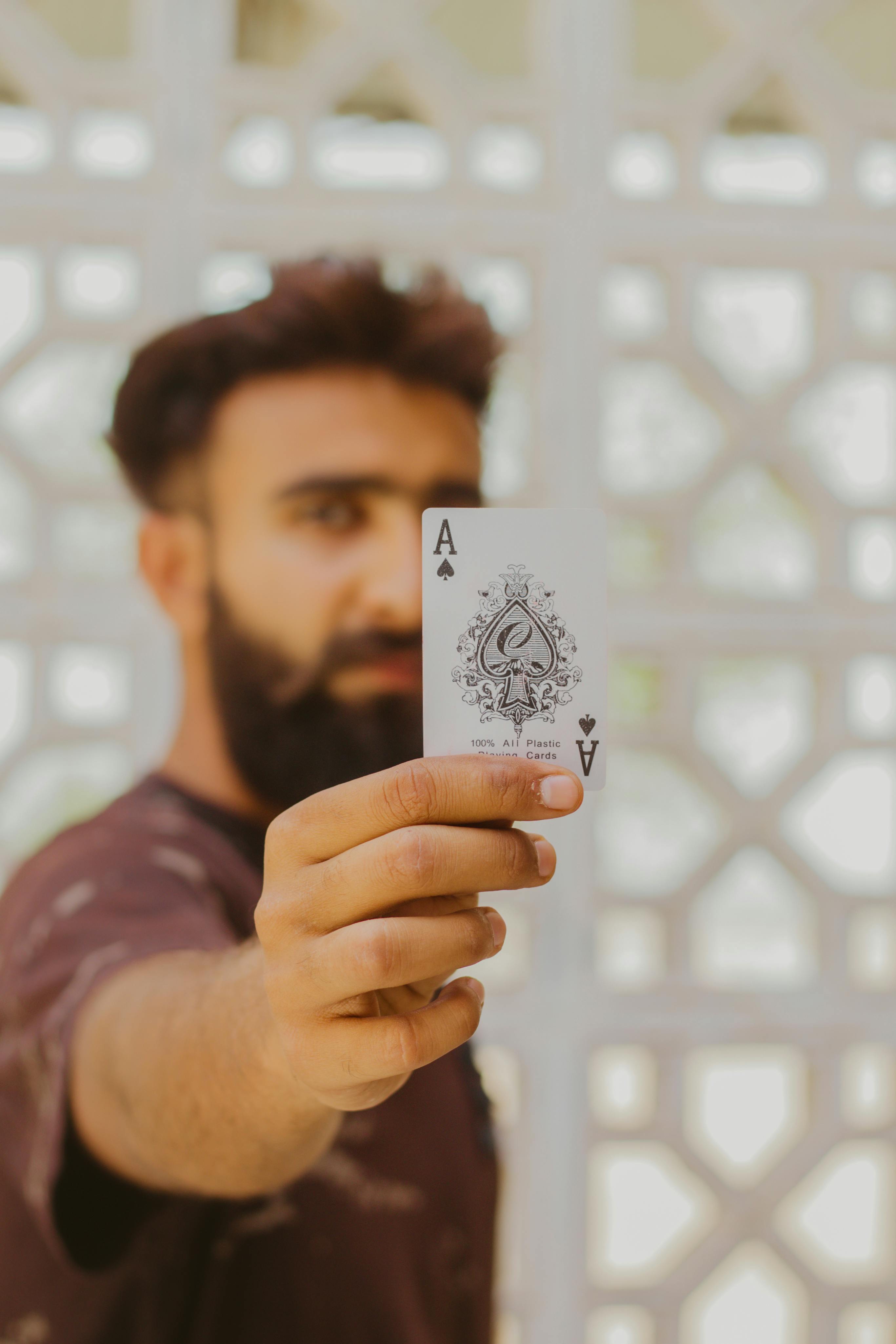 A man holding a single playing card for the camera.