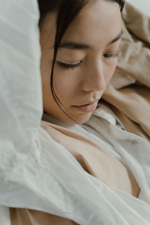 Free Close-up portrait of a woman with serene expression wrapped in soft, flowing fabrics. Stock Photo