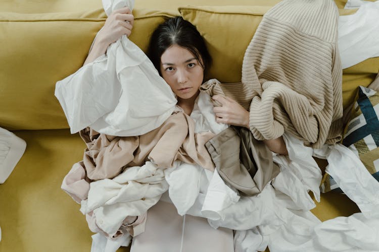 A Woman Reclining On A Coch Covered With Crumpled Clothes