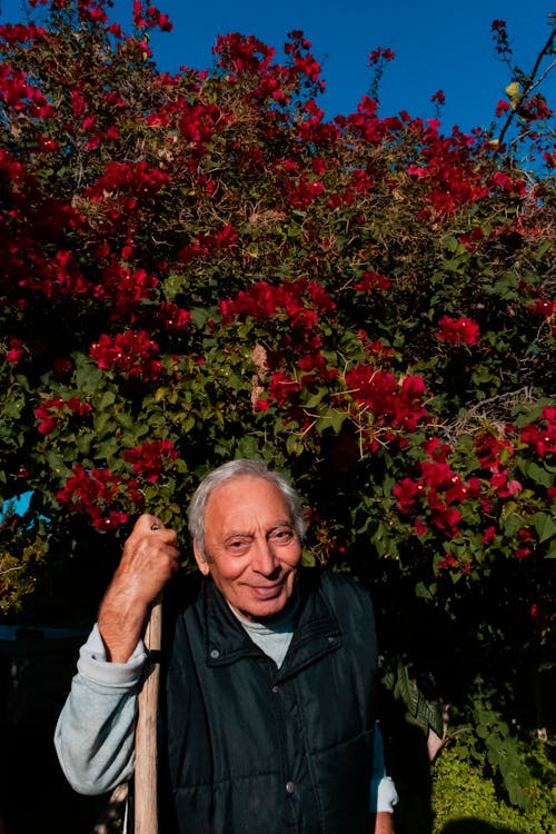 Elderly Man holding Cane standing near Flowers