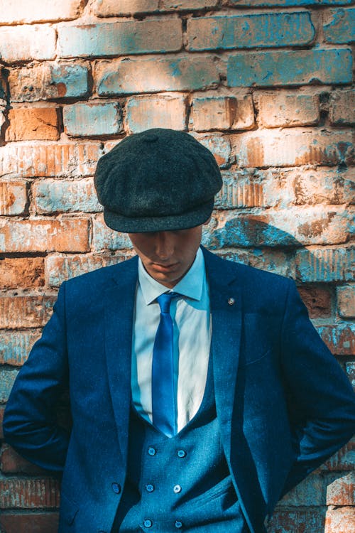 A Man In Suit Wearing a Newspaper Boy Hat
