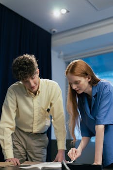 Two colleagues engaged in a work discussion at the office table.