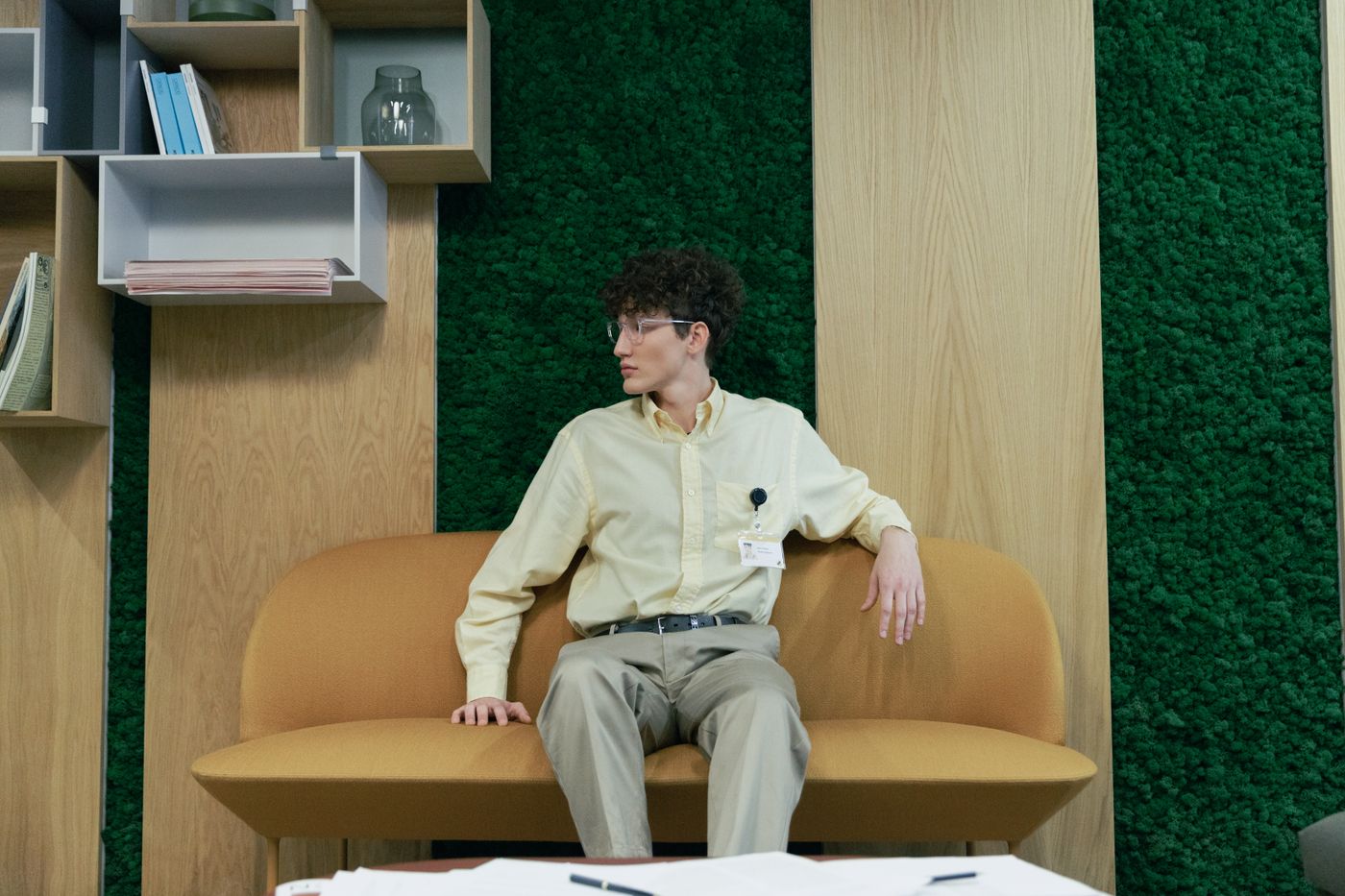A person seated on a lounge sofa against a moss-green office wall, photo by cottonbro studio on Pexels