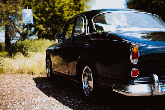 Classic black vintage car parked outdoors on a sunny day, featuring polished chrome details and retro styling.