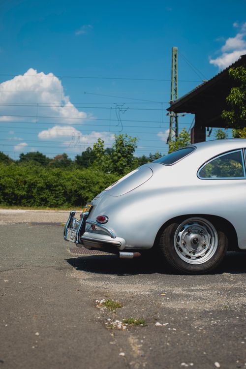 Free Classic silver car parked outdoors on sunny day with blue sky and greenery in background. Stock Photo