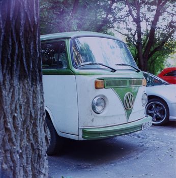 Vintage green and white Volkswagen van parked outdoors beside trees in a serene setting.