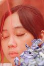 Woman With Eyes Closed Near a Bunch of Purple Flowers