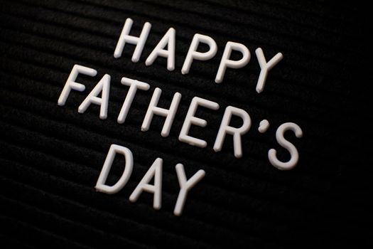 Close-up of 'Happy Father's Day' text in white letters on a black textured background.