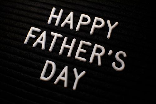 Free Close-up of 'Happy Father's Day' text in white letters on a black textured background. Stock Photo